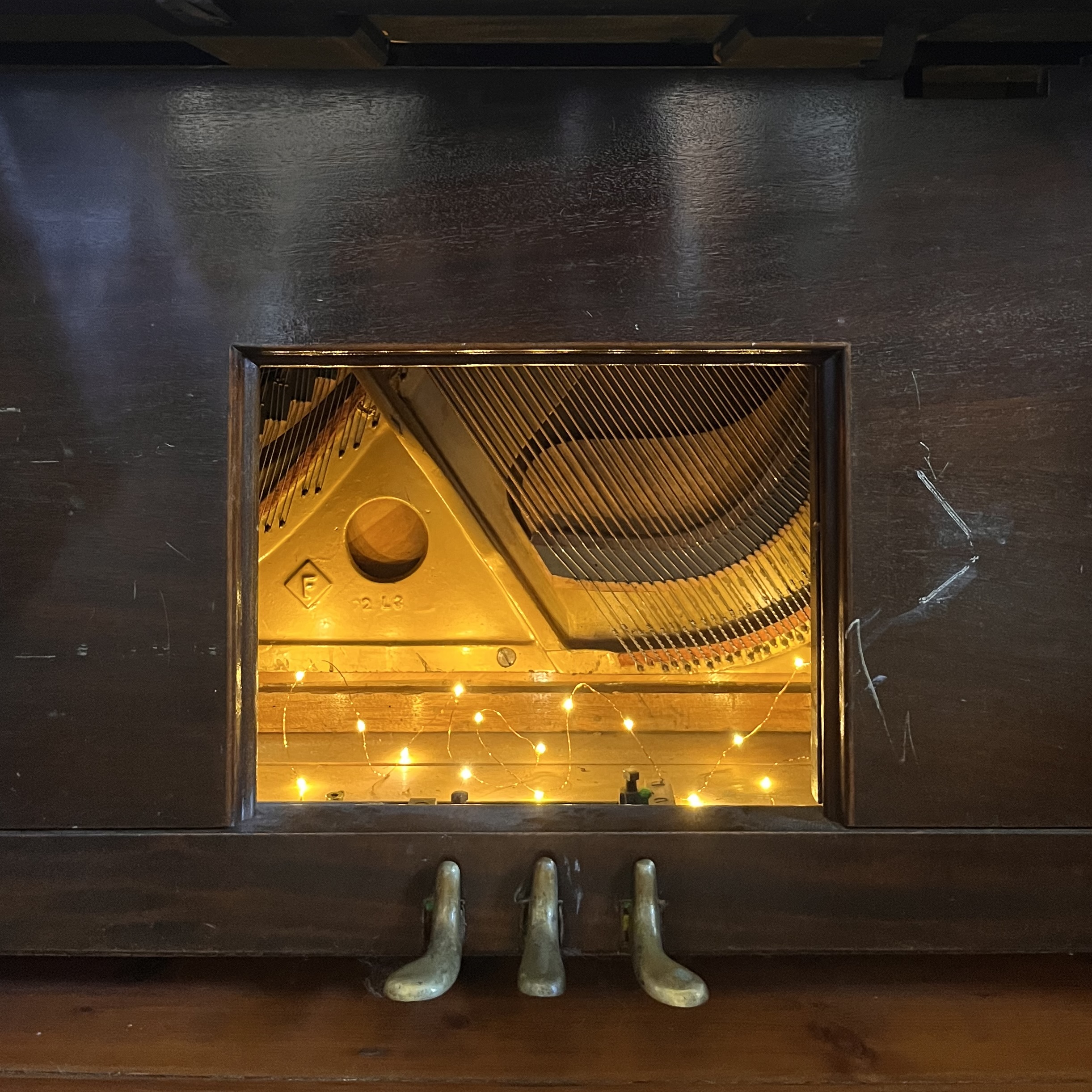 Candle-lit upright piano interior strung with fairy lights